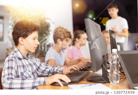 Side view of rows of students in computer class - boys solving computer problems Side view of rows of students in computer class - boys solving computer problems 130772439