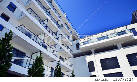 Modern apartment building with balconies and greenery. Beautiful view of real estate buildings in summer. Walking area with trees and grass. Modern residential buildings in the public green area. Modern apartment building with balconies and greenery. Beautiful view of real estate buildings in summer. Walking area with trees and grass. Modern residential buildings in the public green area. 130772524