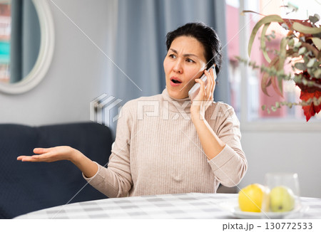 Nervous woman having phone call in apartment 130772533