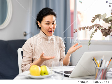Asian woman communicates with someone via video link 130772534