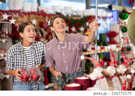 Two cheerful young women choosing Christmas decorations in store Two cheerful young women choosing Christmas decorations in store 130772575