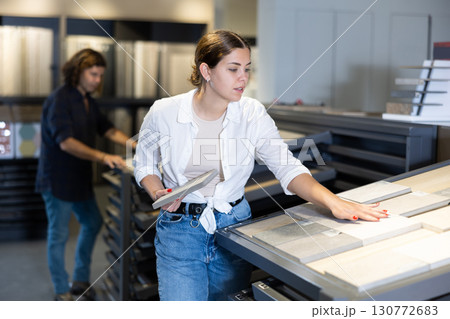 female buyer inspects small decorative tiles for redecorate apartment of new flat. Interior decor female buyer inspects small decorative tiles for redecorate apartment of new flat. Interior decor 130772683