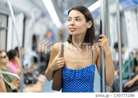 Adult woman stands in subway car Adult woman stands in subway car 130773186