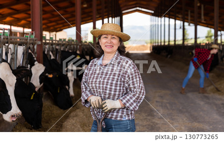 Mature female farmer posing at the cow farm Mature female farmer posing at the cow farm 130773265