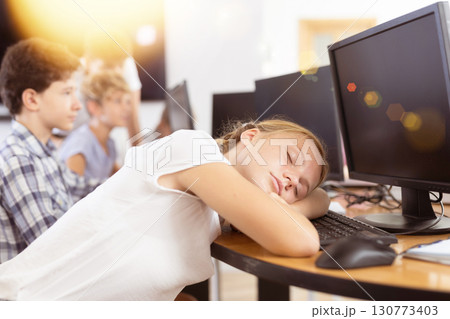 Girl student sleeps while sitting at computer Girl student sleeps while sitting at computer 130773403