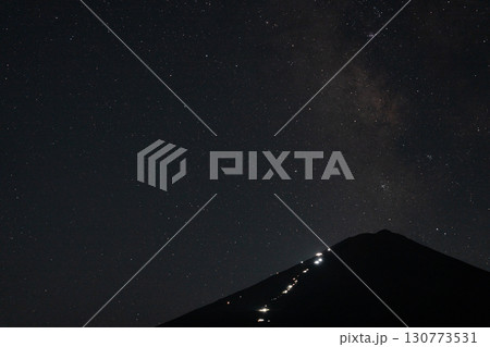 山小屋の明かりが灯る夏の富士山と夜空に広がる天の川 130773531