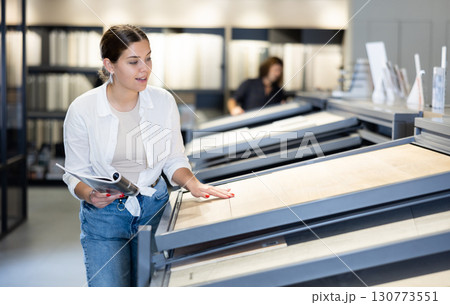Girl customer choosing ceramic tile at building materials store Girl customer choosing ceramic tile at building materials store 130773551
