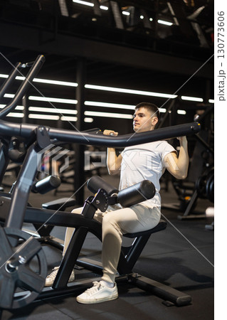Young man training on plate-loaded lat pulldown machine at gym 130773606