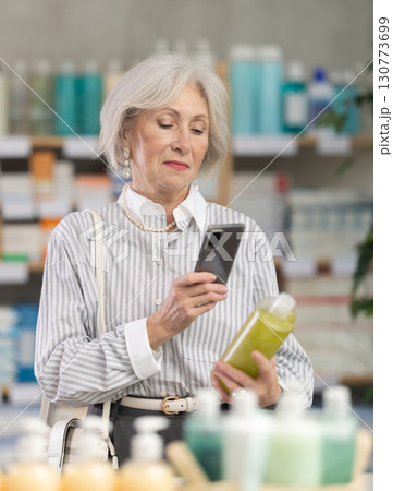 Elderly woman scanning qr code of shampoo Elderly woman scanning qr code of shampoo 130773699