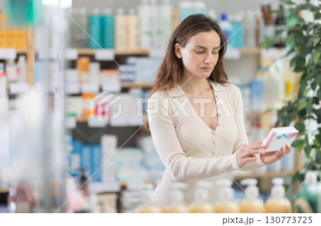 Adult woman chooses pills at pharmacy Adult woman chooses pills at pharmacy 130773725