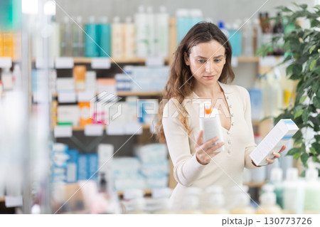 Woman in summer clothes choosing skin cream at drugstore 130773726