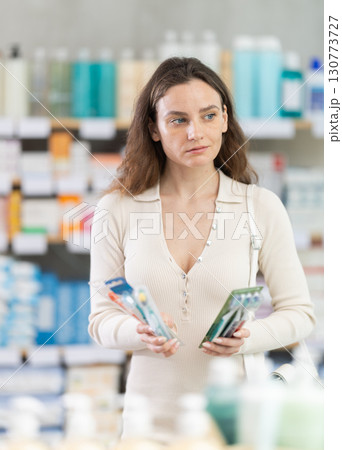 Female shopper chooses toothbrush in supermarket Female shopper chooses toothbrush in supermarket 130773727