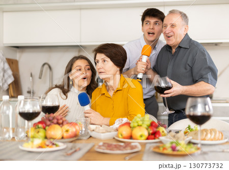 Cheerful multi-generational family singing into microphones at home party 130773732
