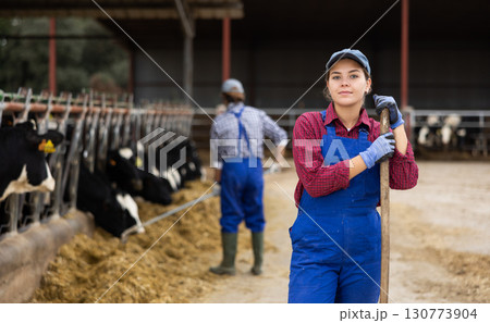 Portrait of successful european female farmer posing in cowshed Portrait of successful european female farmer posing in cowshed 130773904