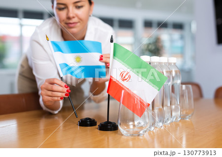 Little flag of Iran on table and flag of Argentina put next to it by young woman 130773913