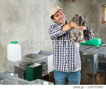 Man farmer with rabbit in her hands on her farm. Farmer takes care of animals 130773963