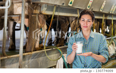 Female with milk glass at milking parlor 130774009
