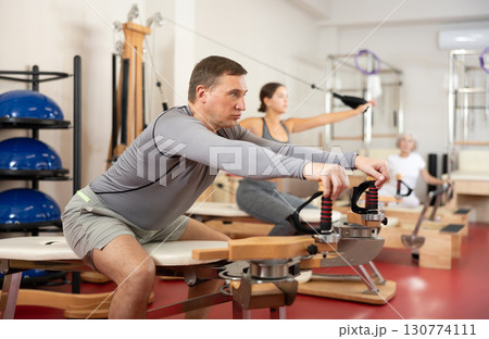 Man during Pilates training performs exercises and tasks on heron pulley tower 130774111