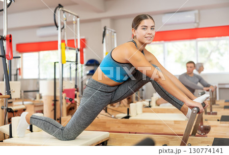 Girl performs exercise on reformer to improve coordination, balance, and posture 130774141