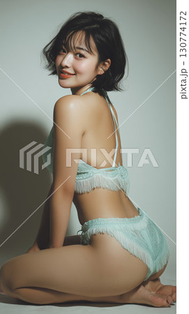 Korean woman posing in a stylish mint green swimsuit with fringe, showcasing a confident smile and playful charm indoors 130774172