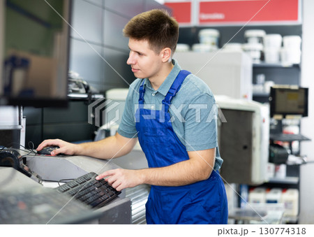 Man worker operating computerised machine to mix paint in paint shop Man worker operating computerised machine to mix paint in paint shop 130774318