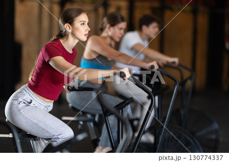 Focused girl works out with airbike during class at fitness club Focused girl works out with airbike during class at fitness club 130774337