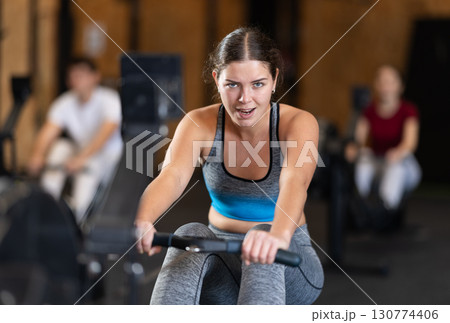 Woman in top exercising on rowing machine 130774406