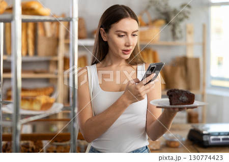 Young girl scanning pastry on paper plate in bakery 130774423
