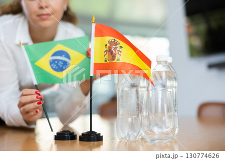 Young woman putting Brazil and Spain flags on table in office Young woman putting Brazil and Spain flags on table in office 130774626