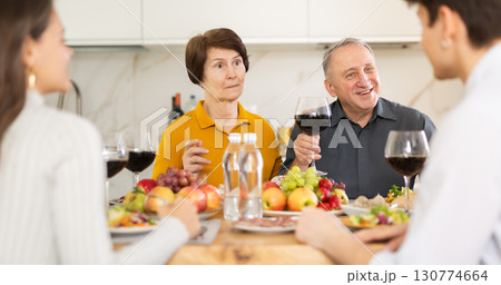 Surprised elderly mother listening to young couple at family dinner 130774664