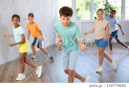 Cheerful tween boy dancing with group of children in choreography class Cheerful tween boy dancing with group of children in choreography class 130774690