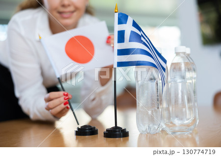 Young female secretary preparing room for international negotiations between greece and japan 130774719