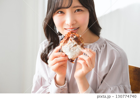 美味しそうにマフィンを食べる若い女性 美味しそうにマフィンを食べる若い女性 130774740