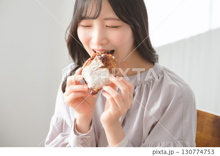 美味しそうにマフィンを食べる若い女性 130774753