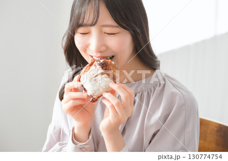 美味しそうにマフィンを食べる若い女性 美味しそうにマフィンを食べる若い女性 130774754