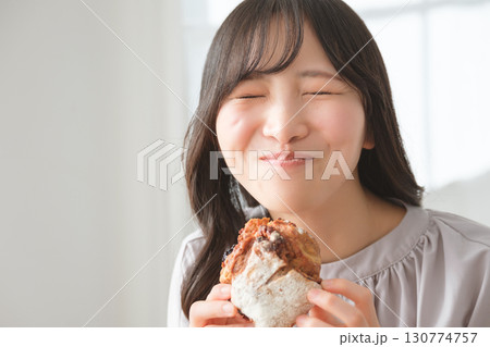 美味しそうにマフィンを食べる若い女性 130774757