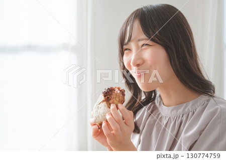 美味しそうにマフィンを食べる若い女性 美味しそうにマフィンを食べる若い女性 130774759