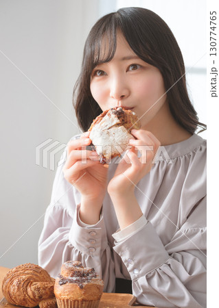 美味しそうにマフィンを食べる若い女性 美味しそうにマフィンを食べる若い女性 130774765