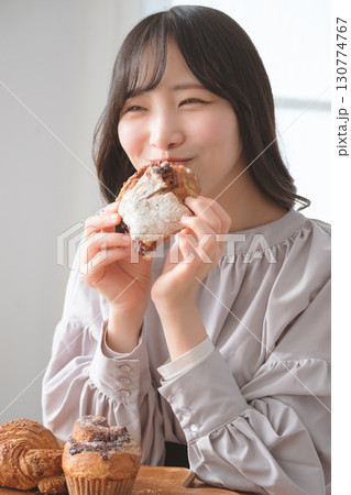 美味しそうにマフィンを食べる若い女性 130774767