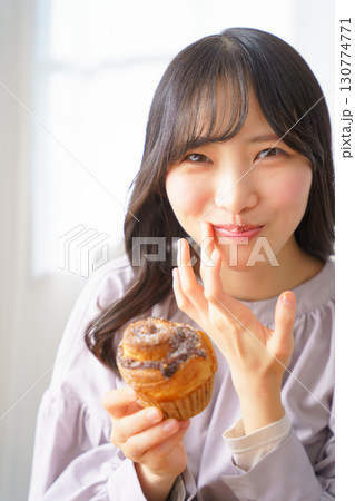 美味しそうにマフィンを食べる若い女性 130774771
