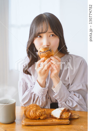美味しそうにマフィンを食べる若い女性 美味しそうにマフィンを食べる若い女性 130774782
