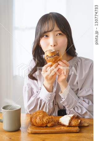 美味しそうにマフィンを食べる若い女性 美味しそうにマフィンを食べる若い女性 130774783