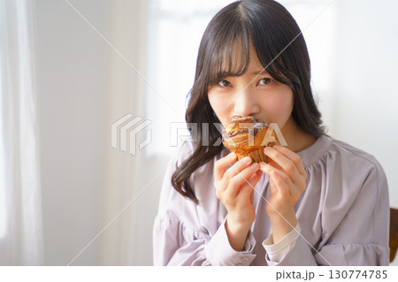 美味しそうにマフィンを食べる若い女性 美味しそうにマフィンを食べる若い女性 130774785