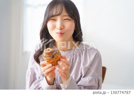 美味しそうにマフィンを食べる若い女性 130774787