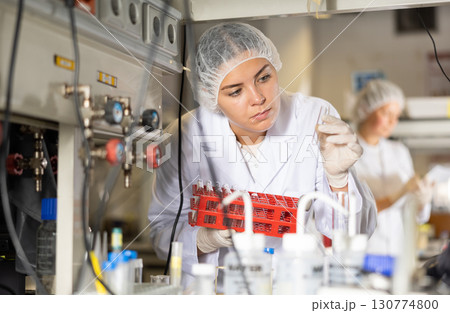 Female scientist researcher looking at reaction in test tube while performing biochemical tests in lab Female scientist researcher looking at reaction in test tube while performing biochemical tests in lab 130774800