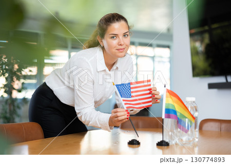 Young lady sets miniatures flags of LGBT and USA before international negotiations Young lady sets miniatures flags of LGBT and USA before international negotiations 130774893