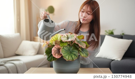 リビングに置かれた植物に水をやる女性 130774948