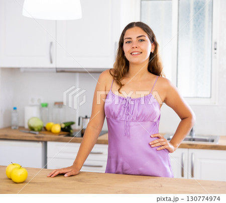 Young housewife in purple nightgown posing in kitchen 130774974