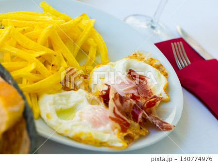 Fried eggs with Iberico ham and potatoes 130774976