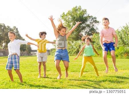 Group of children jumping together on green grass 130775051